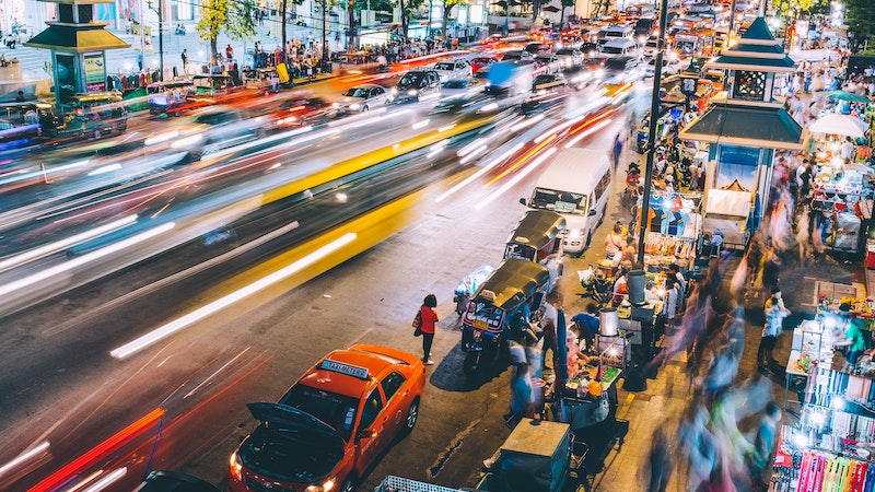A busy Thailand street at nighttime with car lights speeding past