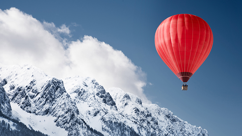 Colorful hot-air balloon flying over snowcapped mountain