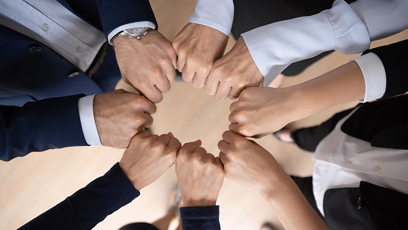 Business team showing expressing strong motivation, engaged in teambuilding activity, making hand circle, keeping fists together. Teamwork, community, corporate friendship concept. Close up, top view