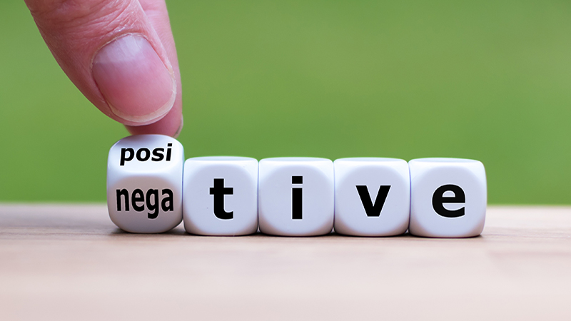 Hand turns a dice and changes the expression "negative" to "positive".