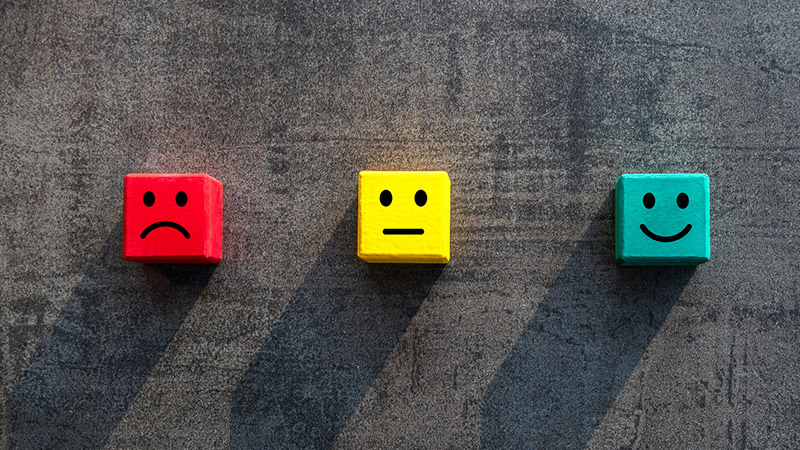 Unhappy okay and happy faces on coloured red yellow green wood blocks