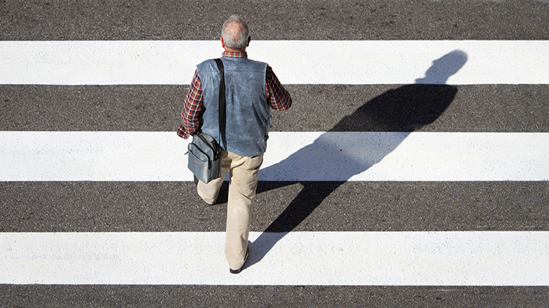 Retirement concept. Scene of a senior man walking in a cebra crossing towards retirement text. Top view