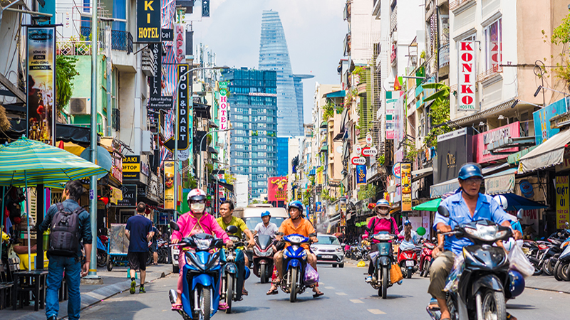 Bui Vien Street perspective, numerous signboards, people, motorbikes, Bitexco Tower. The colorful area is famous Saigon tourist attraction located in District 1, Ho Chi Minh City, Vietnam.