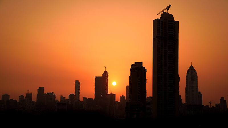 Panorama of South Mumbai's skyline with sun setting behind newly constructed tall towers in silhouette. Copy space.