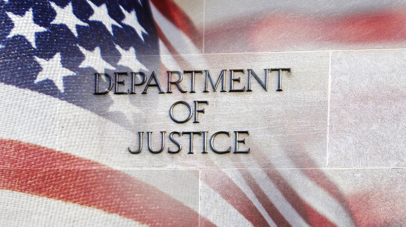 Department of Justice building sign with an American flag behind it