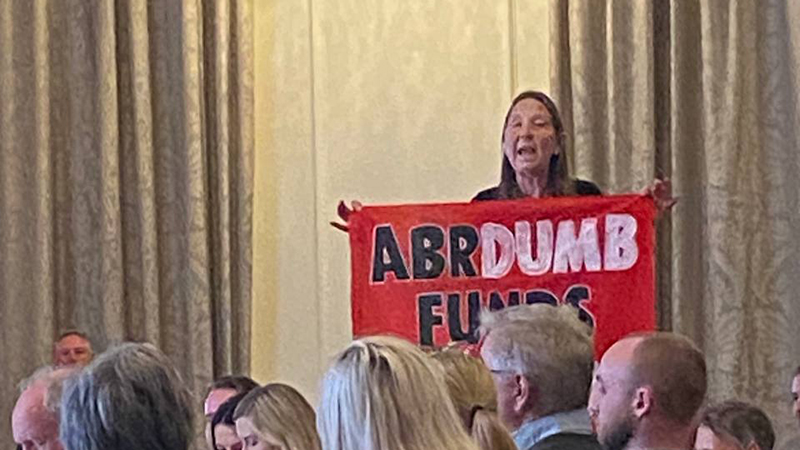Tipping Point UK activist with banner inside AGM