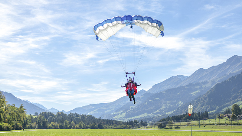 Paraglider comes in to land on grassy meadow