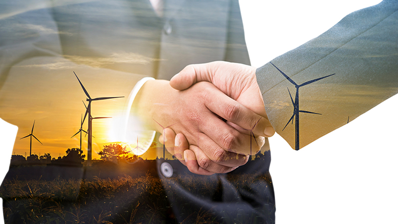 Double exposure of business handshake partnership with wind turbine farm plant background