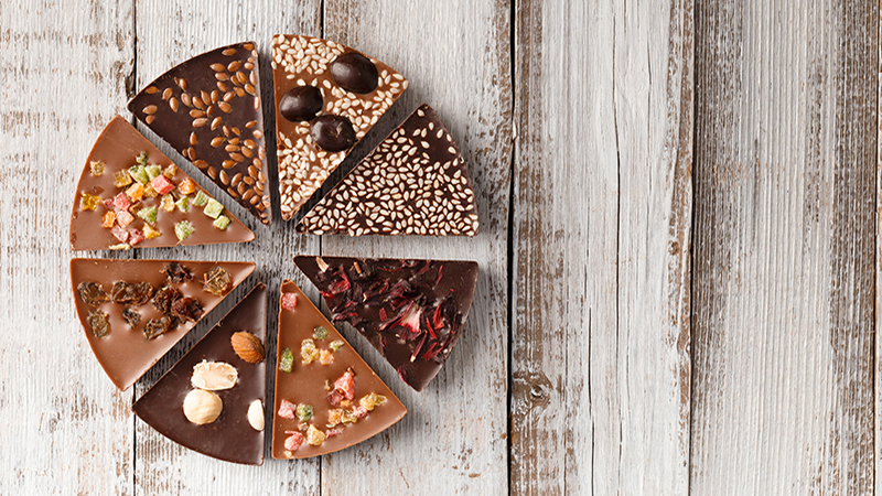 Creative composition chocolate in the shape of a pizza with candied fruits, nuts, dry berries, chocolate pizza and ingredients on a wooden background copy space.