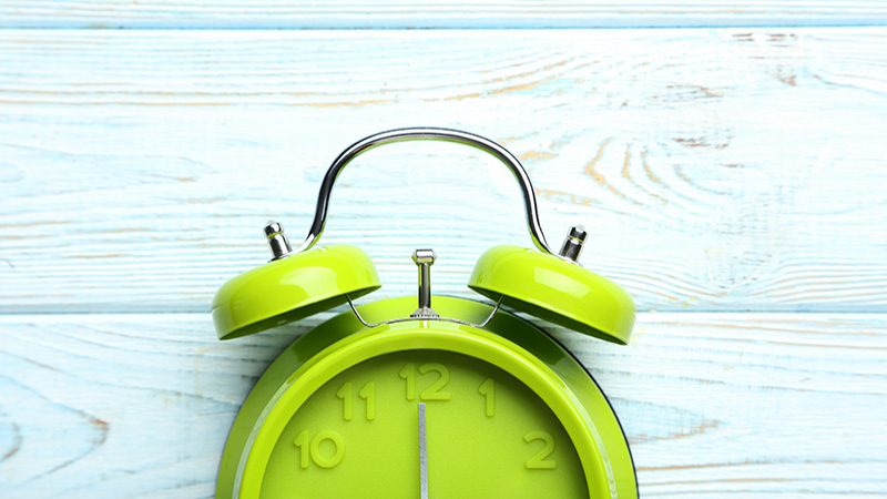 Green alarm clock on a blue wooden table