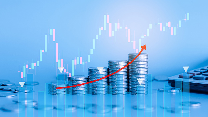 Stack of money coin and calculator with trading graph and chart. Business and finance background with blue filter.