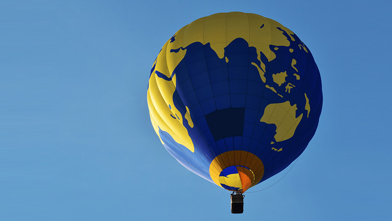 Colourful blue and yellow hot air balloon in flight on sky