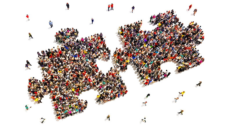 Large group of people in the shape of two puzzle pieces on a white background.