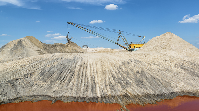 "Another planet" industrial landscape with a walking excavator working in a titanium quarry with intense red color of water