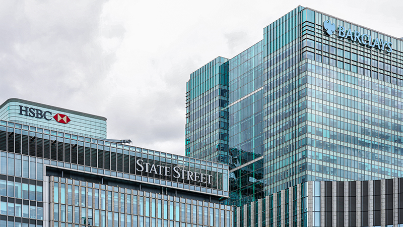 London, England, UK - 04 June 2025: An exterior view of the State Street, Barclays International (One Churchill Place Building), HSBC headquarters high-rise building (8 Canada Square Tower) in Canary Wharf, East London, UK. The modern glass and steel tower features the company’s signage displayed on its facade.